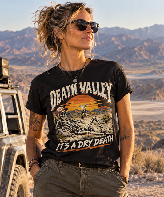 A woman wearing a death valley skeleton t-shirt, black graphic tee, skull in sunglasses illustration, desert sunset badge design, martini cocktail graphic, vintage travel style print, cracked desert landscape art, dry humor streetwear shirt, unisex crew neck shirt