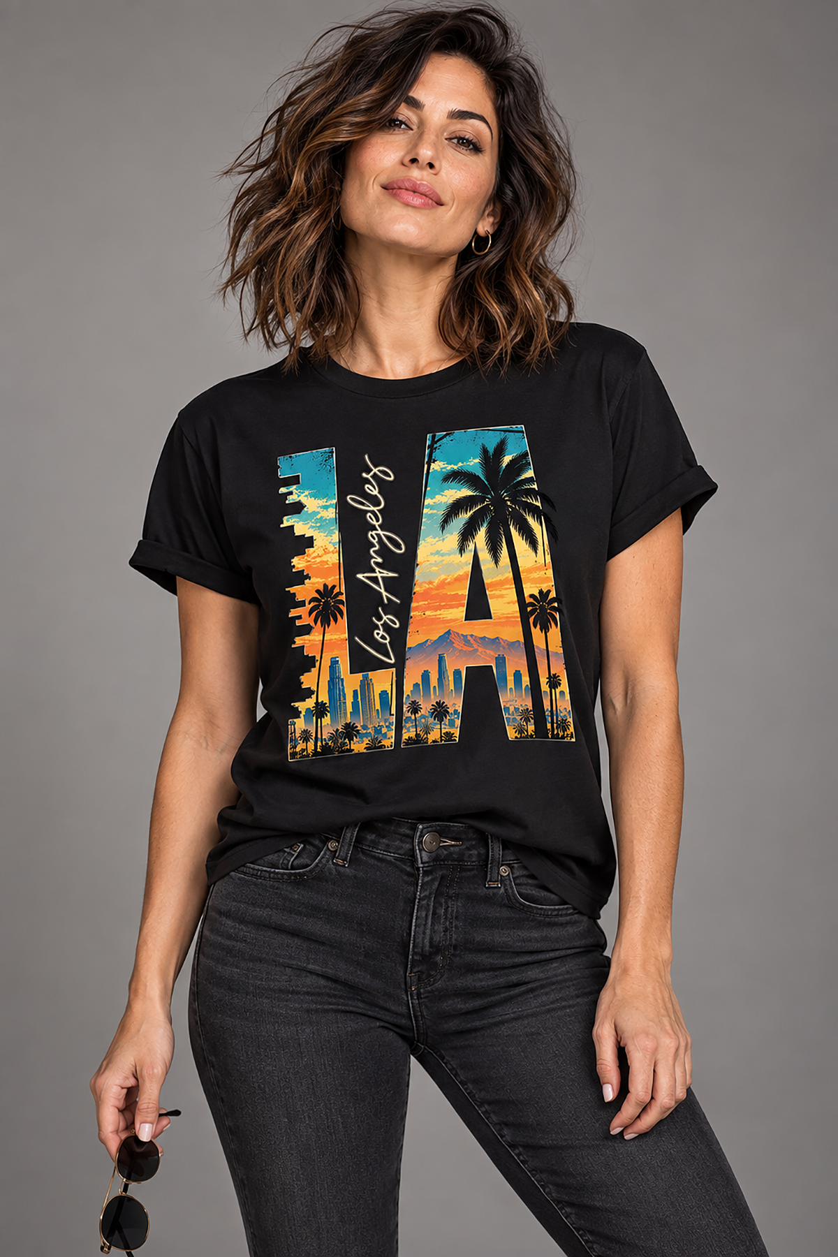 A woman modeling a los angeles t-shirt, black graphic tee, la letterform skyline design, downtown los angeles sunset graphic, palm tree cityscape illustration, west coast streetwear shirt, city of angels print design, sunset skyline art, vintage travel style graphic, unisex crew neck shirt