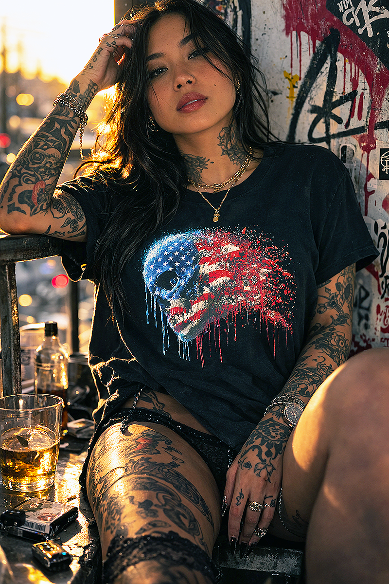 Red White and Ruin American flag skull graphic tee worn by tattooed Asian female model on rooftop balcony at golden hour whiskey graffiti wall black t-shirt