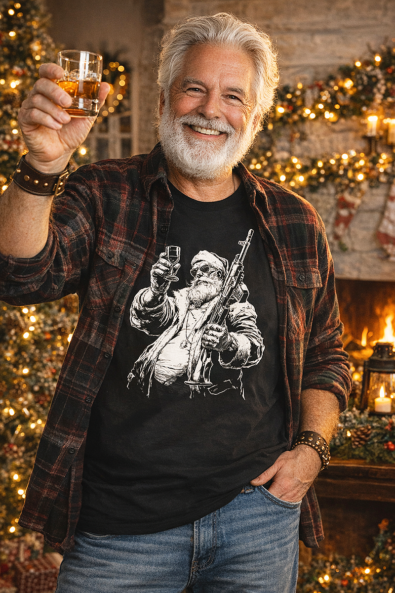 Redneck Santa funny Christmas gun Santa graphic tee worn by silver-haired male model in flannel shirt raising whiskey glass at holiday fireplace black t-shirt