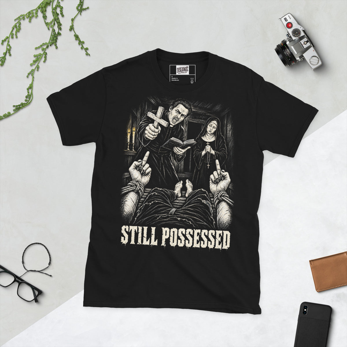 still possessed t-shirt, black graphic tee, gothic exorcism illustration, priest and nun horror design, bound demon hands graphic, defiant gesture horror print, candlelit dark scene art, distressed horror typography, black and white horror illustration, unisex crew neck shirt