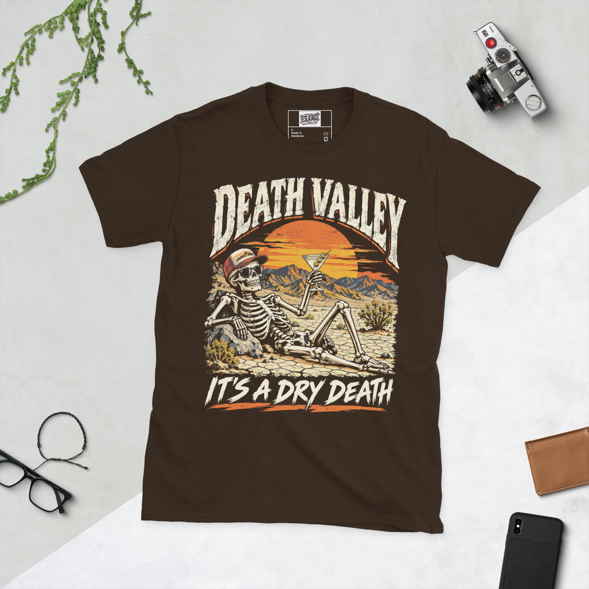 death valley skeleton t-shirt, brown graphic tee, skull in sunglasses illustration, desert sunset badge design, martini cocktail graphic, vintage travel style print, cracked desert landscape art, dry humor streetwear shirt, unisex crew neck shirt